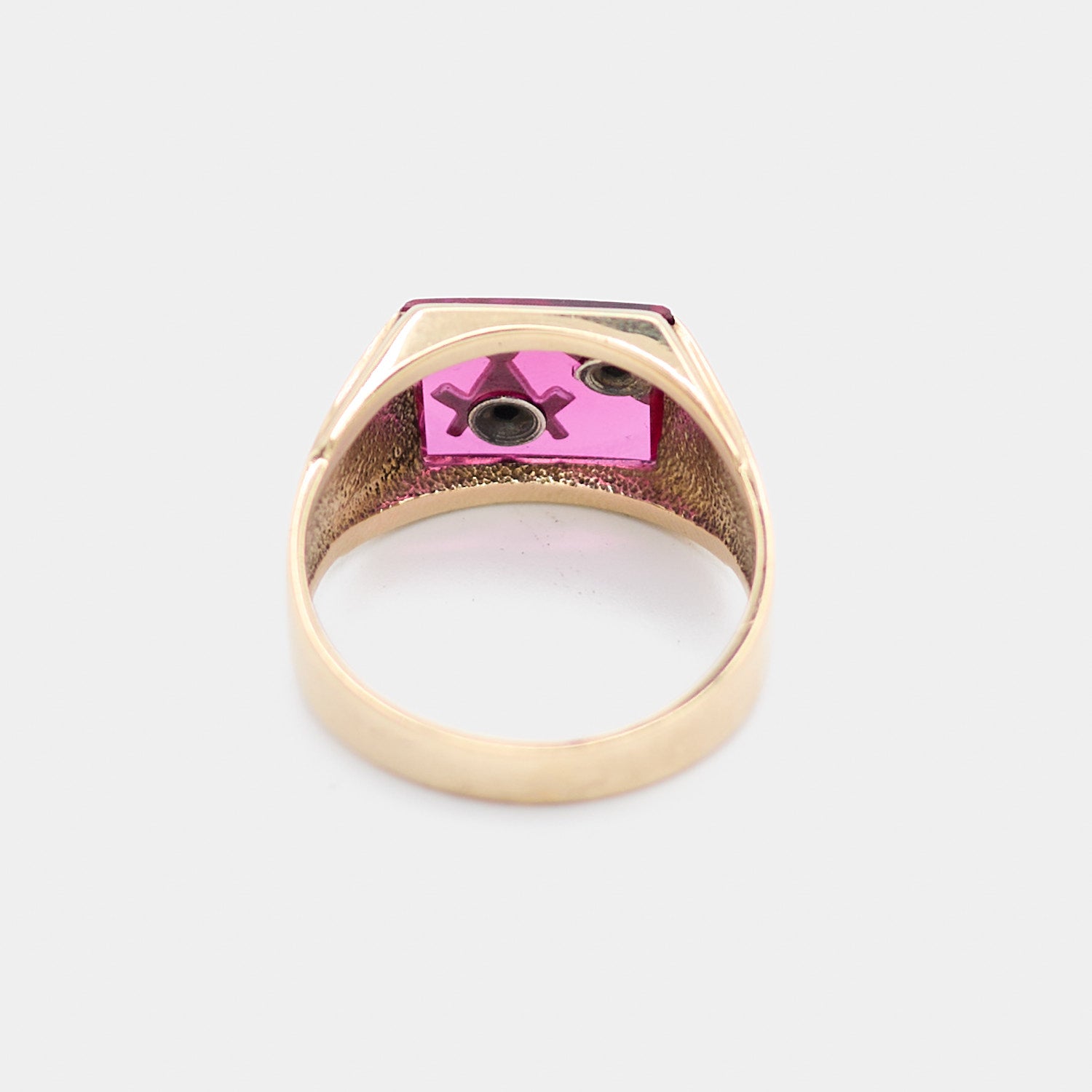 Underside view of a pre-owned 10K yellow gold Freemason ring showing the prong settings securing the red center stone and gallery structure of the band. Weighs 6.78 grams, size 9.5.