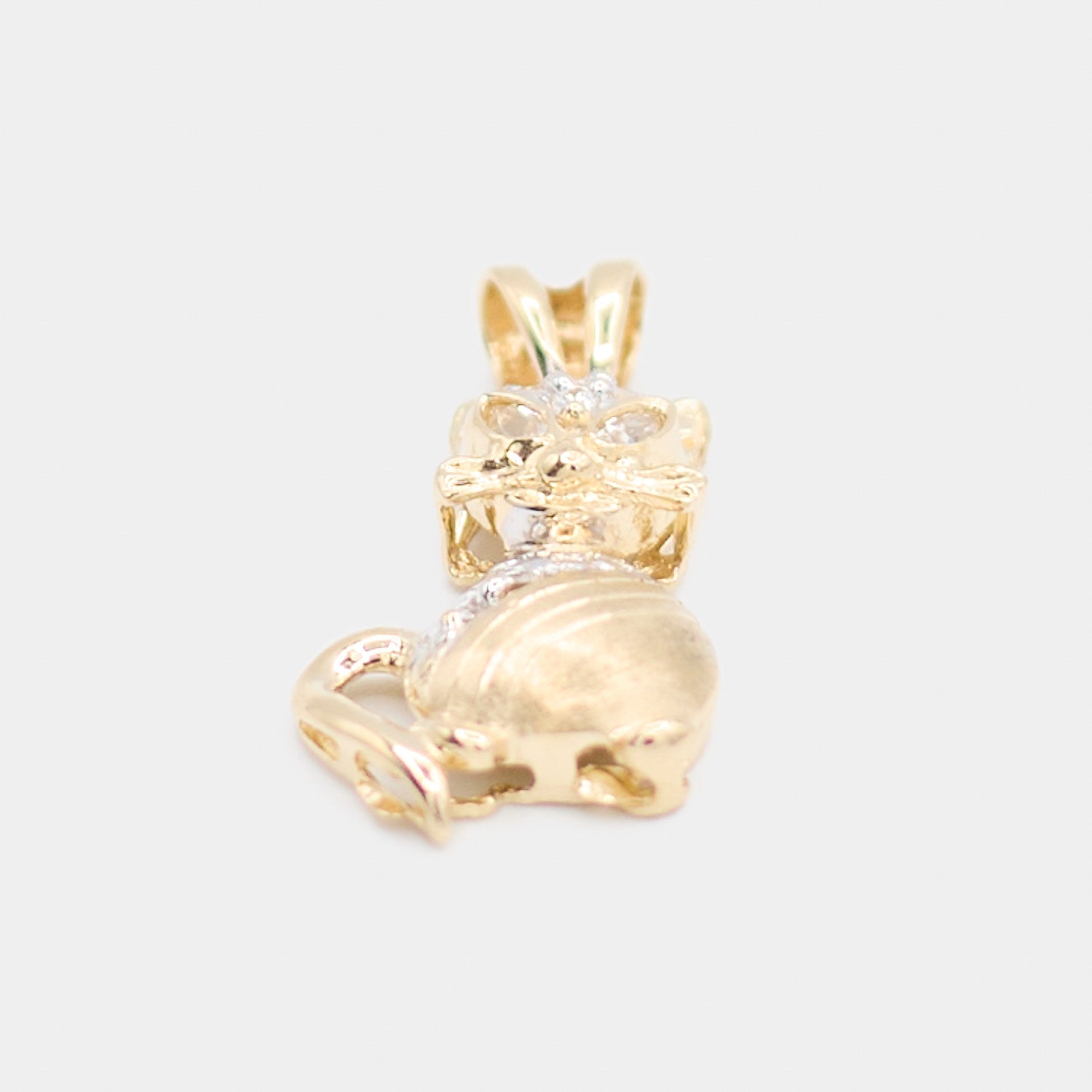 Angled view of a pre-owned 14K yellow gold cat charm showing the curled tail design and white stone accents along the face and back.
