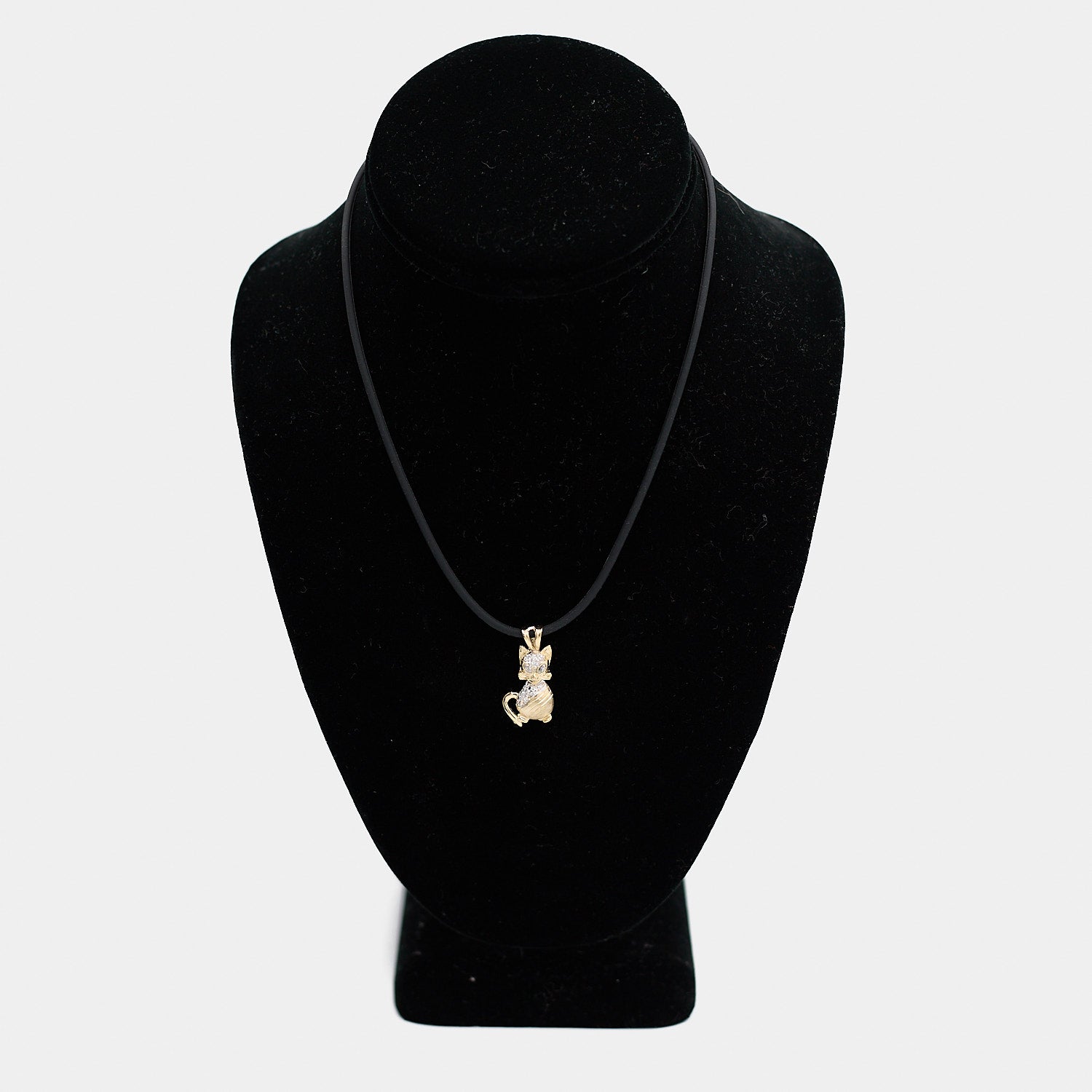 Pre-owned 14K yellow gold cat charm with white stone accents, shown on a black cord necklace against a display bust. Charm measures 1 1/8 inch.