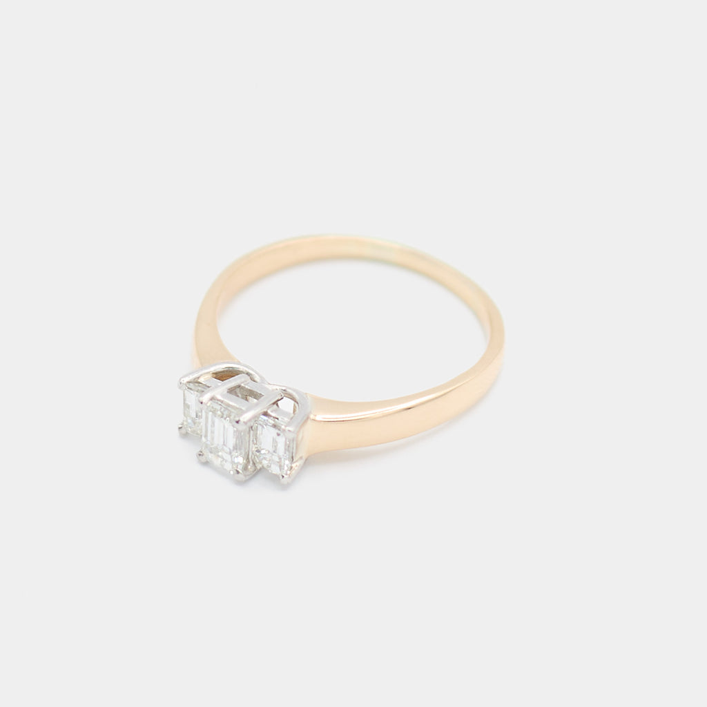 Angled 3/4 view of a pre-owned 14K yellow gold engagement ring showing the three emerald cut diamonds and prong setting detail.