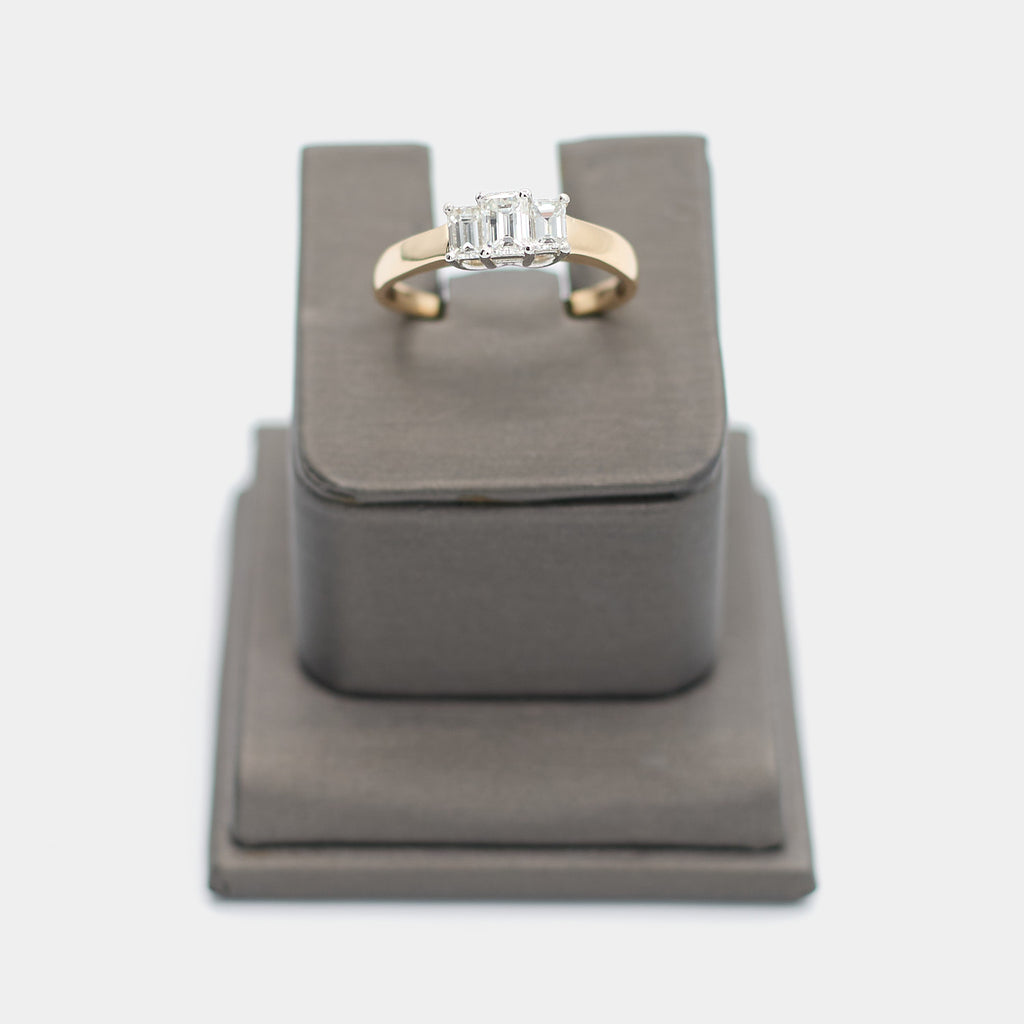 Pre-owned 14K yellow gold engagement ring with three emerald cut diamonds in white gold prong settings, shown front-facing on a display stand. Size 9.5.