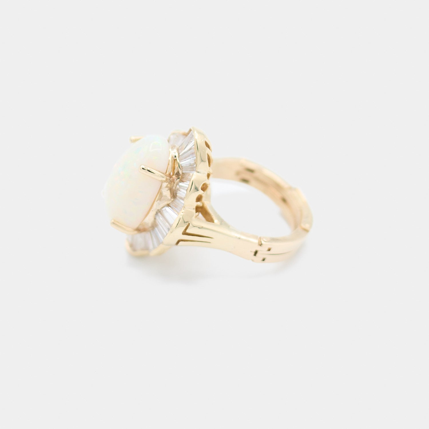 Side profile of a pre-owned 14K yellow gold opal ring showing the depth of the baguette diamond halo and prong setting.