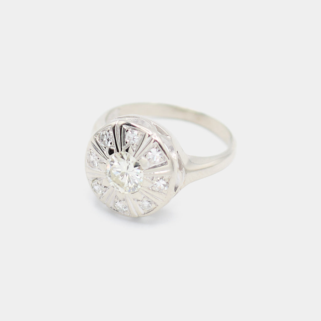 Angled view of a pre-owned 14K white gold Art Deco diamond ring showing the engraved sunburst design and center diamond halo setting.