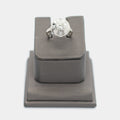Pre-owned 14K white gold Art Deco diamond ring, size 5.75, featuring a round center diamond surrounded by 8 smaller diamonds in a sunburst pattern, shown front-facing on a display stand.