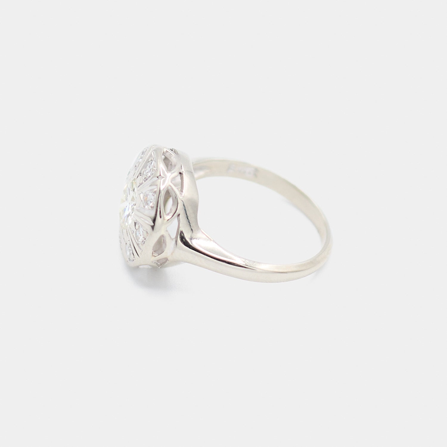 Side profile of a pre-owned 14K white gold Art Deco diamond ring showing the open filigree gallery and quatrefoil cutout detail beneath the diamond face.
