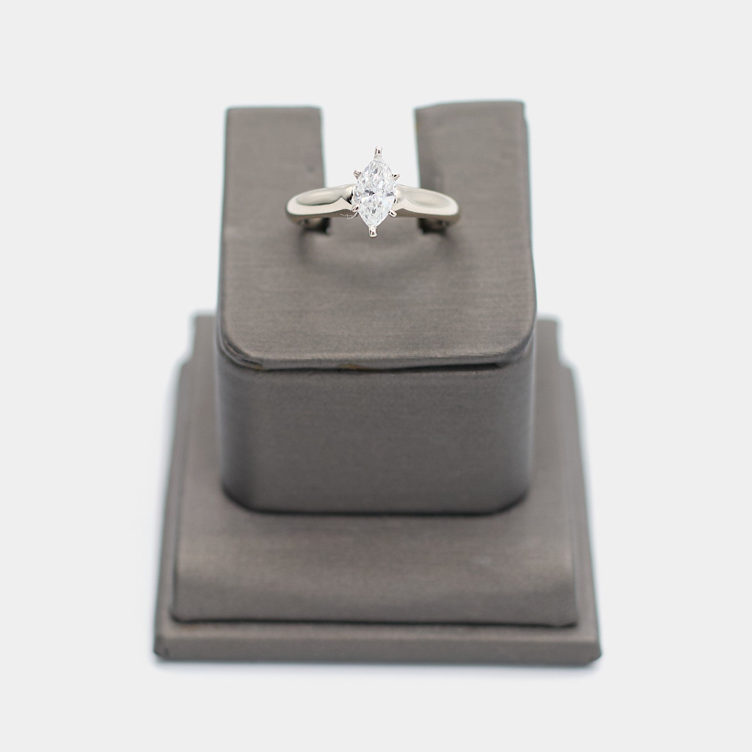 Pre-owned 14K white gold engagement ring with a marquise cut diamond in a six prong setting, shown front-facing on a display stand. Size 5.5.