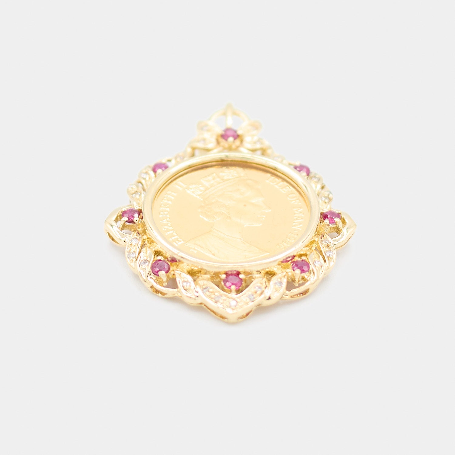 Angled view of a pre-owned 18K yellow gold coin pendant showing the depth of the scalloped bezel setting with red stone and diamond accents.
