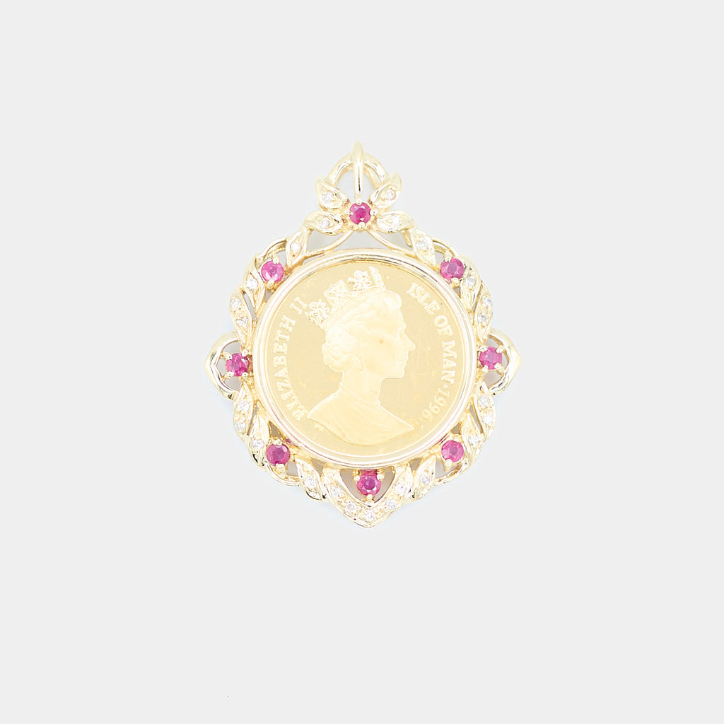 Close-up front view of a pre-owned 18K yellow gold bezel pendant featuring a 24K gold 1996 Isle of Man coin, surrounded by red stones and diamonds in a scalloped leaf design.