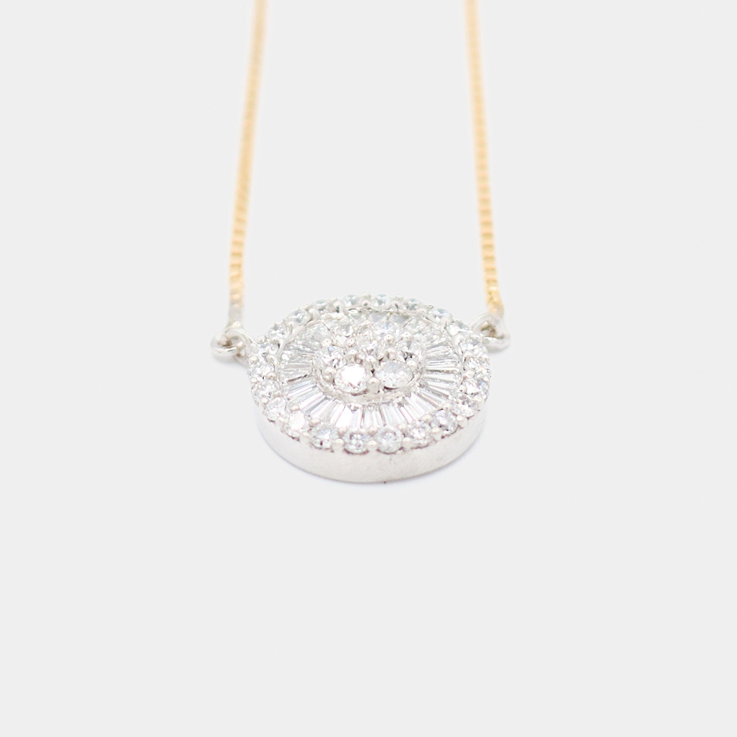 Angled front view of a pre-owned 18K white gold diamond pendant necklace, showing the depth and dimension of the round and baguette diamond halo setting.
