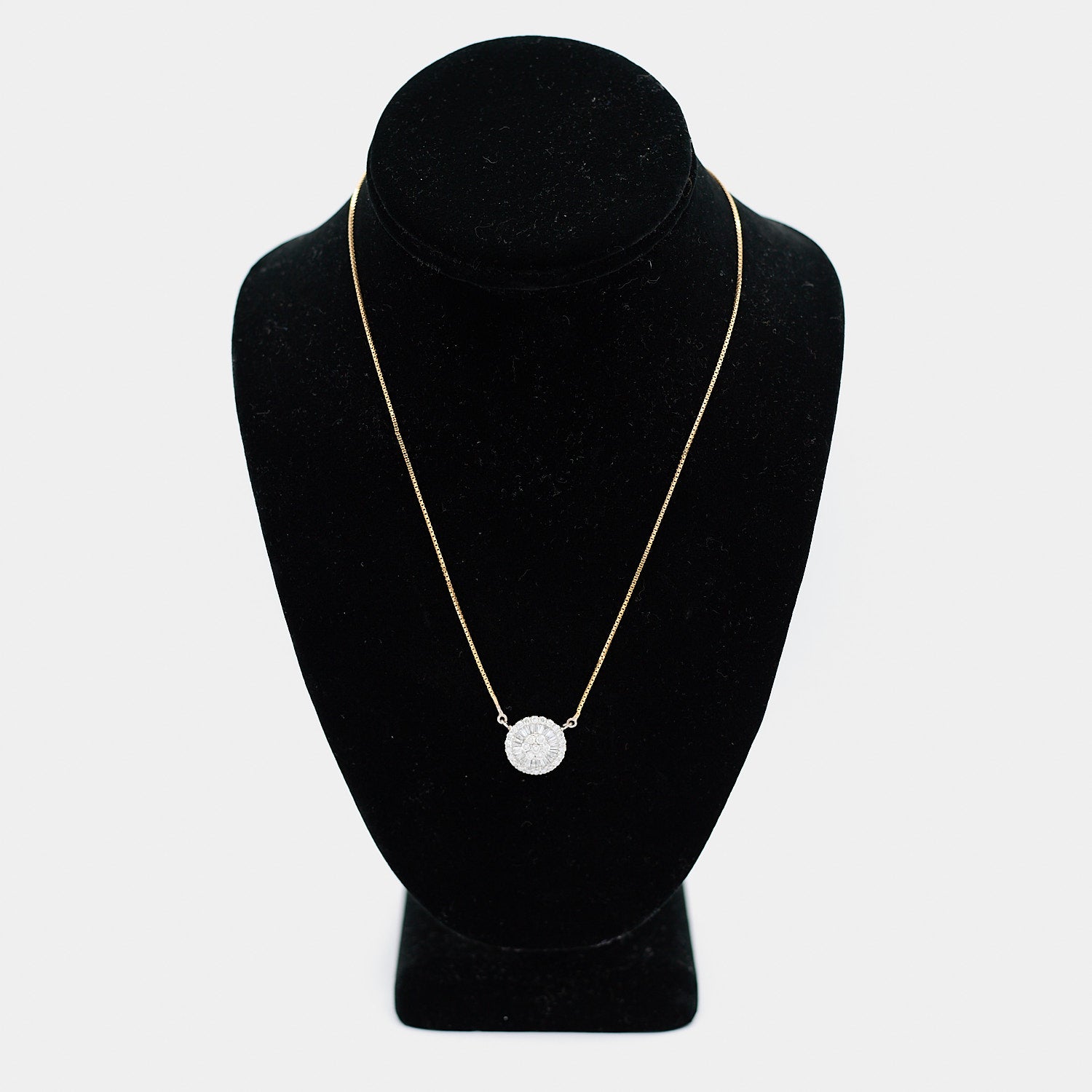 Pre-owned 18K yellow gold box chain necklace with a white gold diamond pendant, featuring round and tapered baguette diamonds in a circular halo design, shown on a display bust. 18 inch chain.