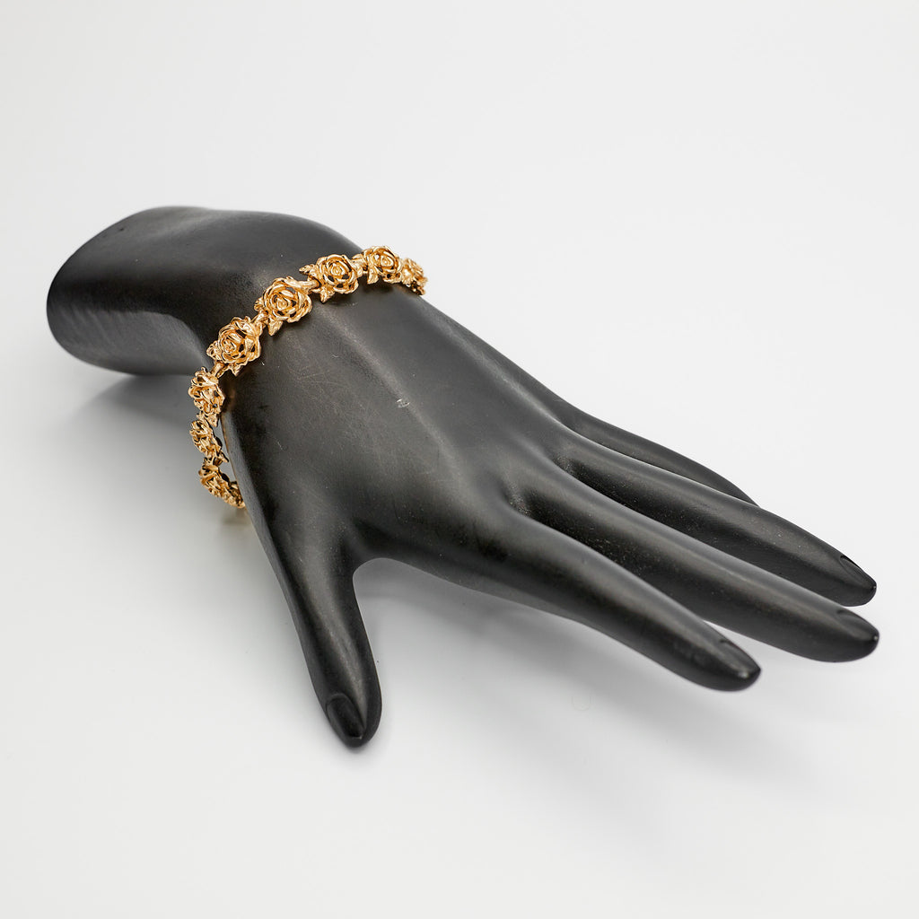 14K Gold Flower Link Bracelet on black mannequin hand on white background
