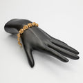 14K Gold Flower Link Bracelet on black mannequin hand on white background