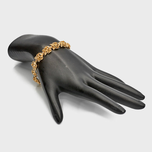 14K Gold Flower Link Bracelet on black mannequin hand on white background