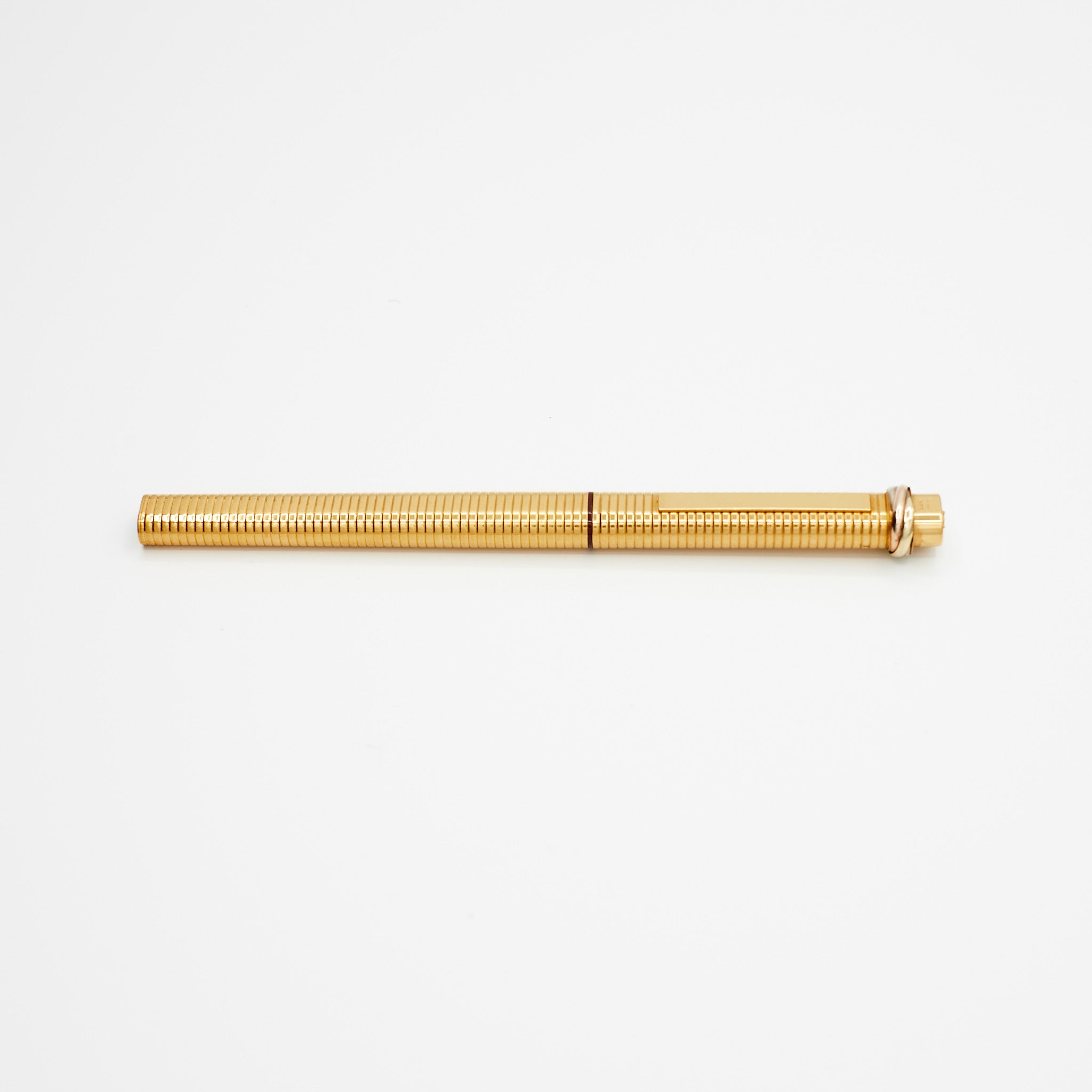 Gold-plated vintage Cartier ballpoint pen resting on a white background, side view.