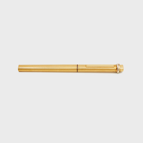 Gold-plated vintage Cartier ballpoint pen resting on a white background, side view.