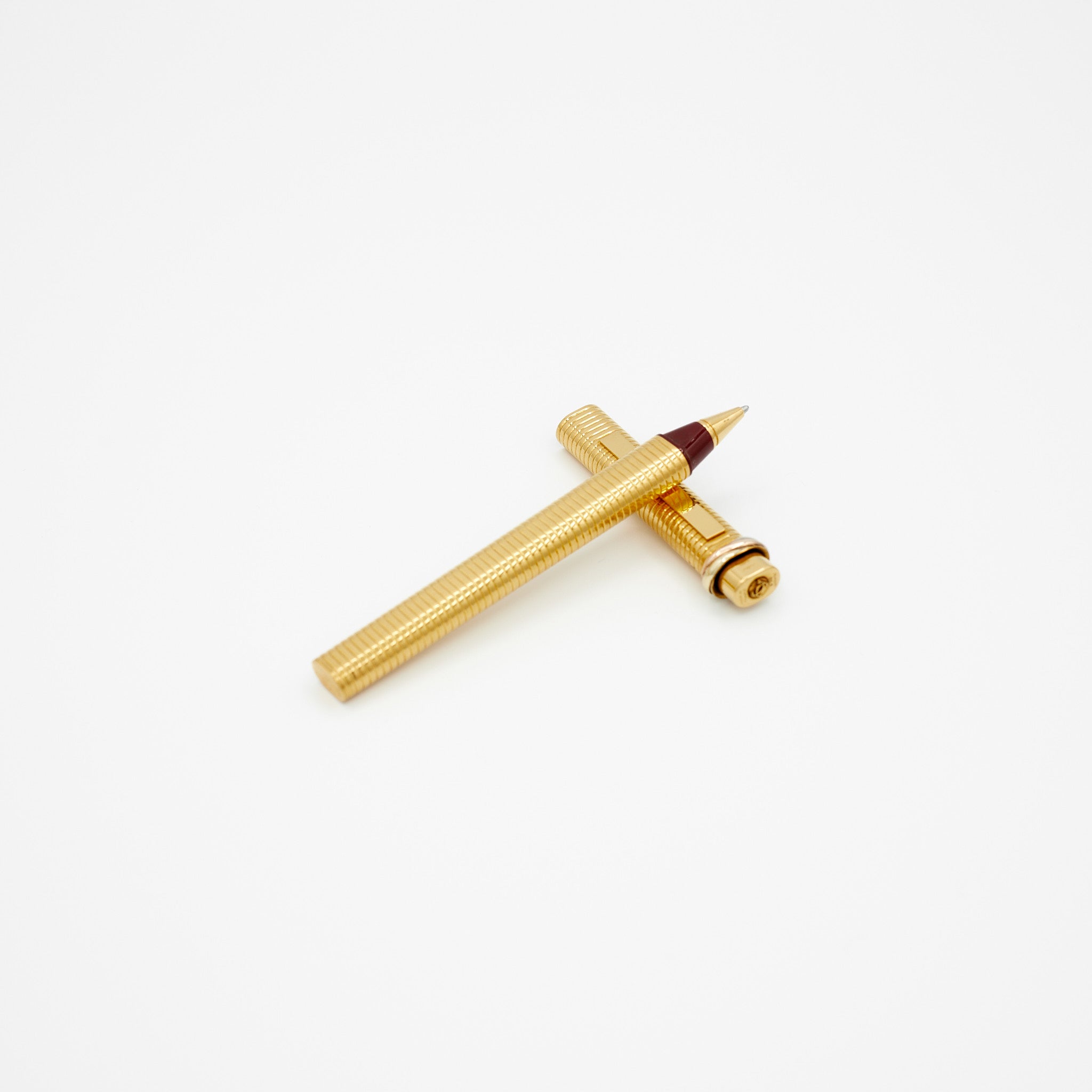 Cartier gold-plated vintage ballpoint pen on white background laying on it's cap.