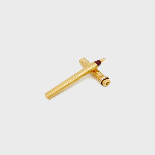 Cartier gold-plated vintage ballpoint pen on white background laying on it's cap.