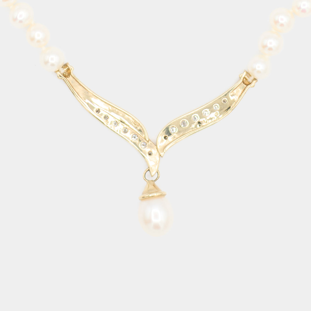 Close-up back view of a pre-owned pearl necklace's 10K gold centerpiece, showing the diamond settings and 10K hallmark stamp. 