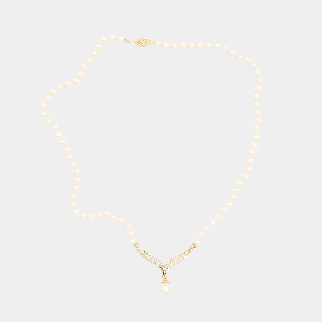 Full length back view of a pre-owned pearl necklace laid flat, showing the complete pearl strand and gold centerpiece from behind.