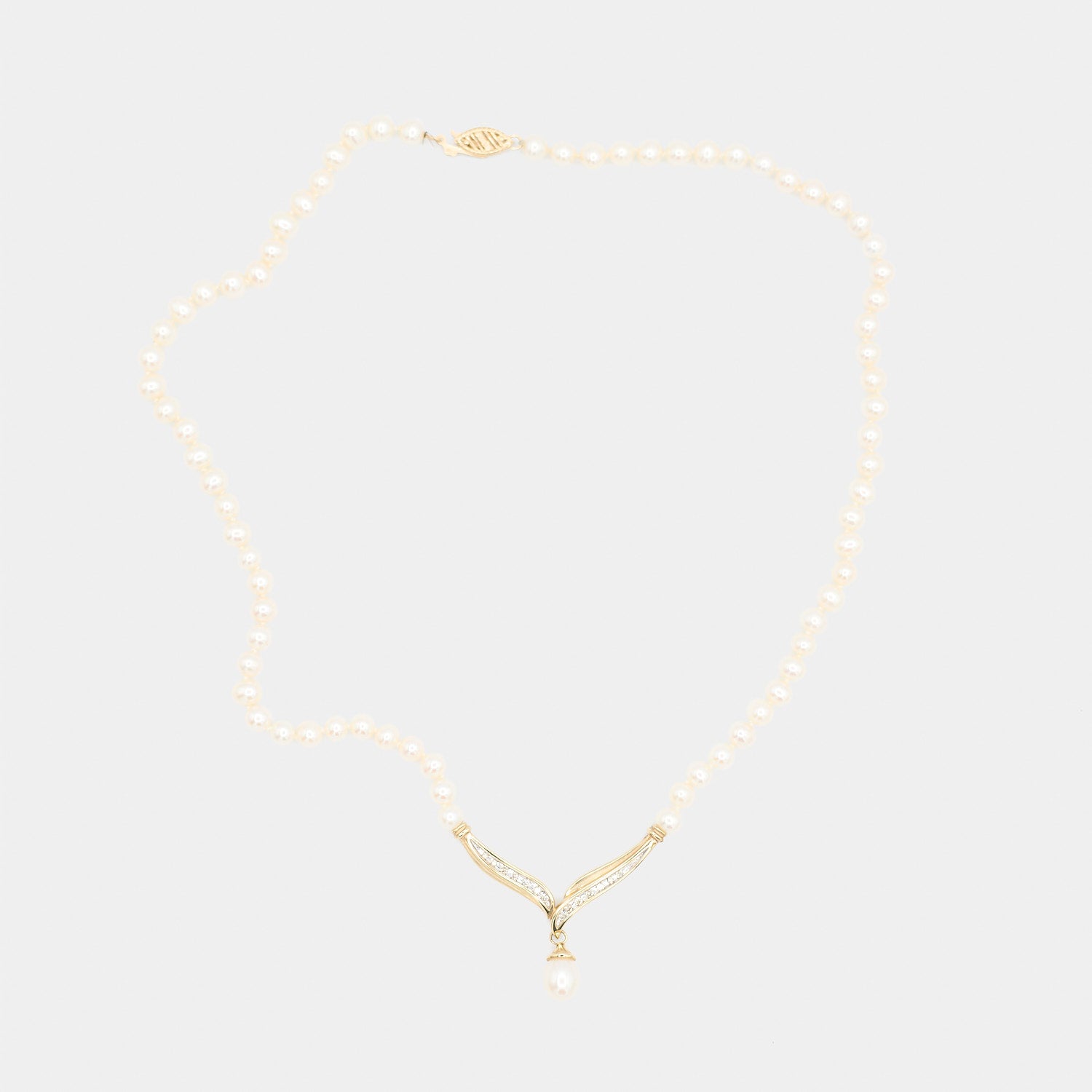 Full length back view of a pre-owned pearl necklace laid flat, showing the complete pearl strand and gold centerpiece from behind.
