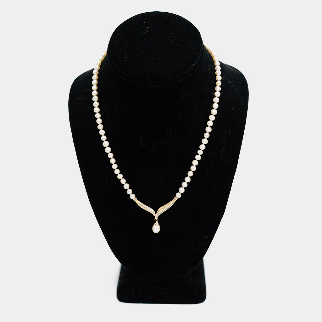 Pre-owned pearl necklace with a 10K gold diamond centerpiece and dangling pearl drop, shown on a display bust. Necklace measures 18 inches.