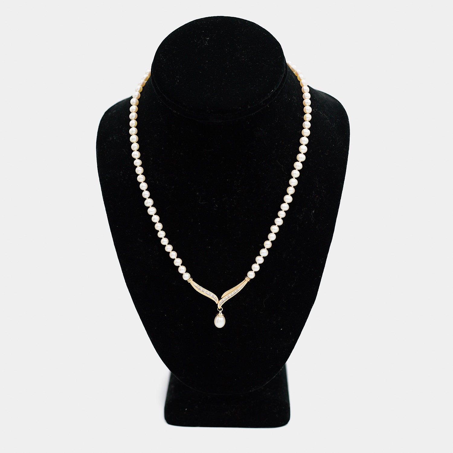 Pre-owned pearl necklace with a 10K gold diamond centerpiece and dangling pearl drop, shown on a display bust. Necklace measures 18 inches.