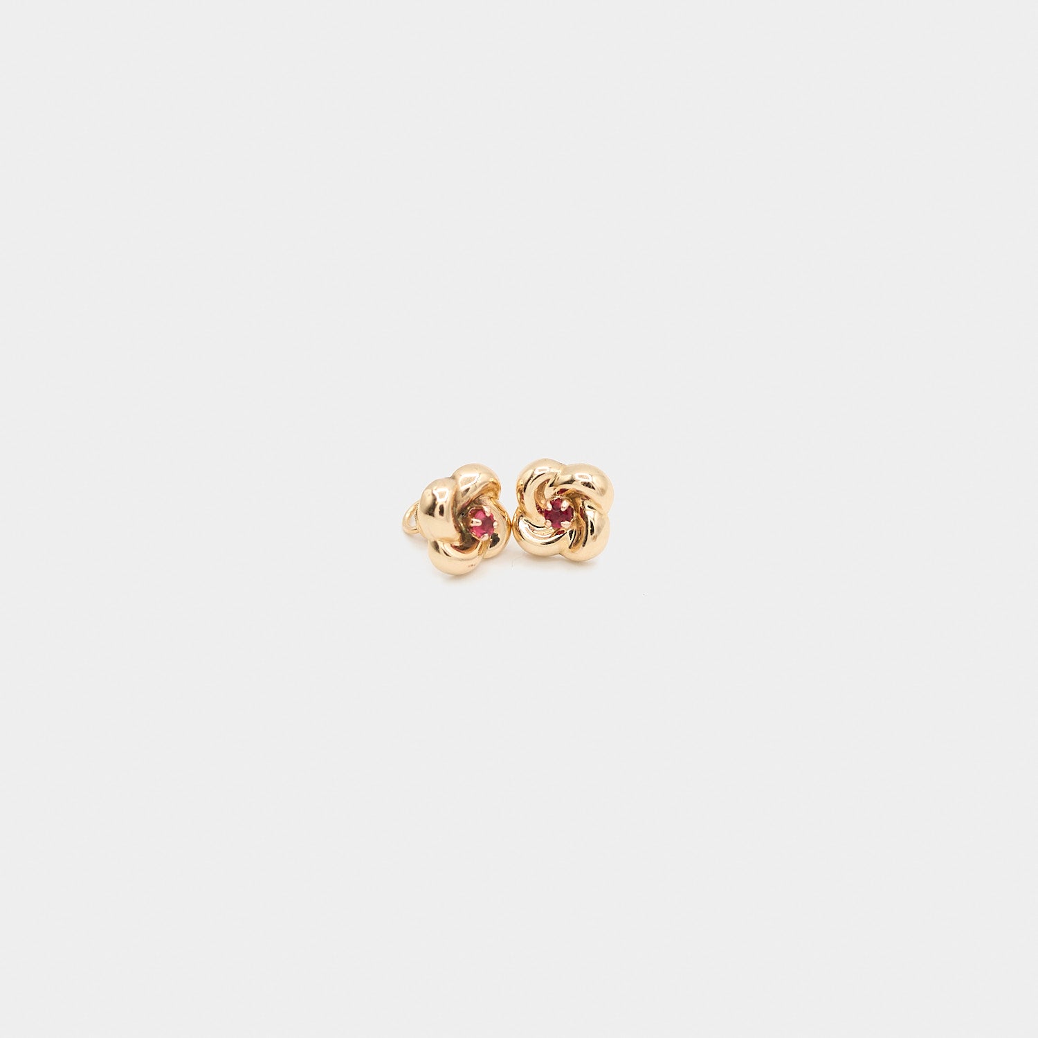 Close-up view of the 10K yellow gold flower earrings with red stone centers, highlighting the detailed petals and 3.51 gram total weight.