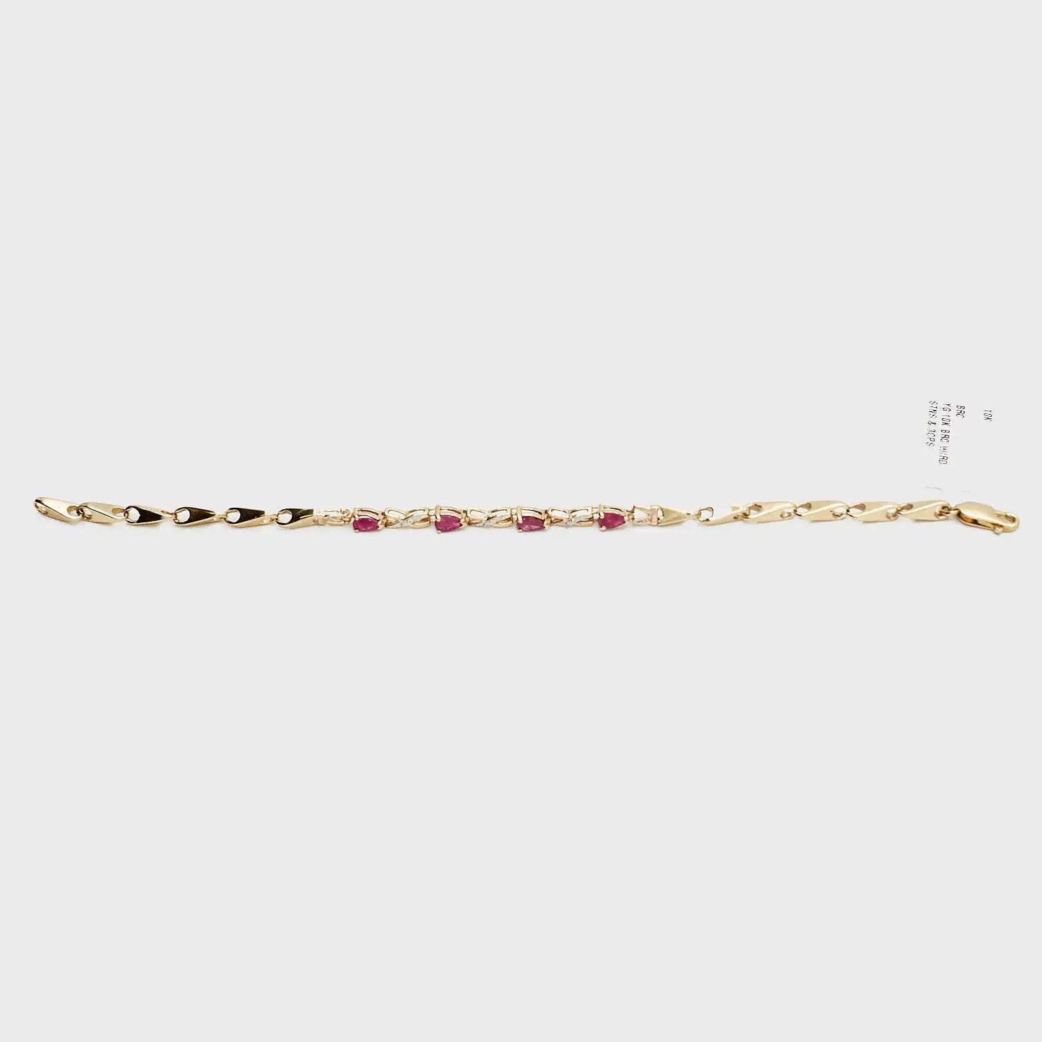 Close-up view of the 10K gold red stone and diamond bracelet, laid flat, showcasing the precise stone settings and 7.71 gram weight.