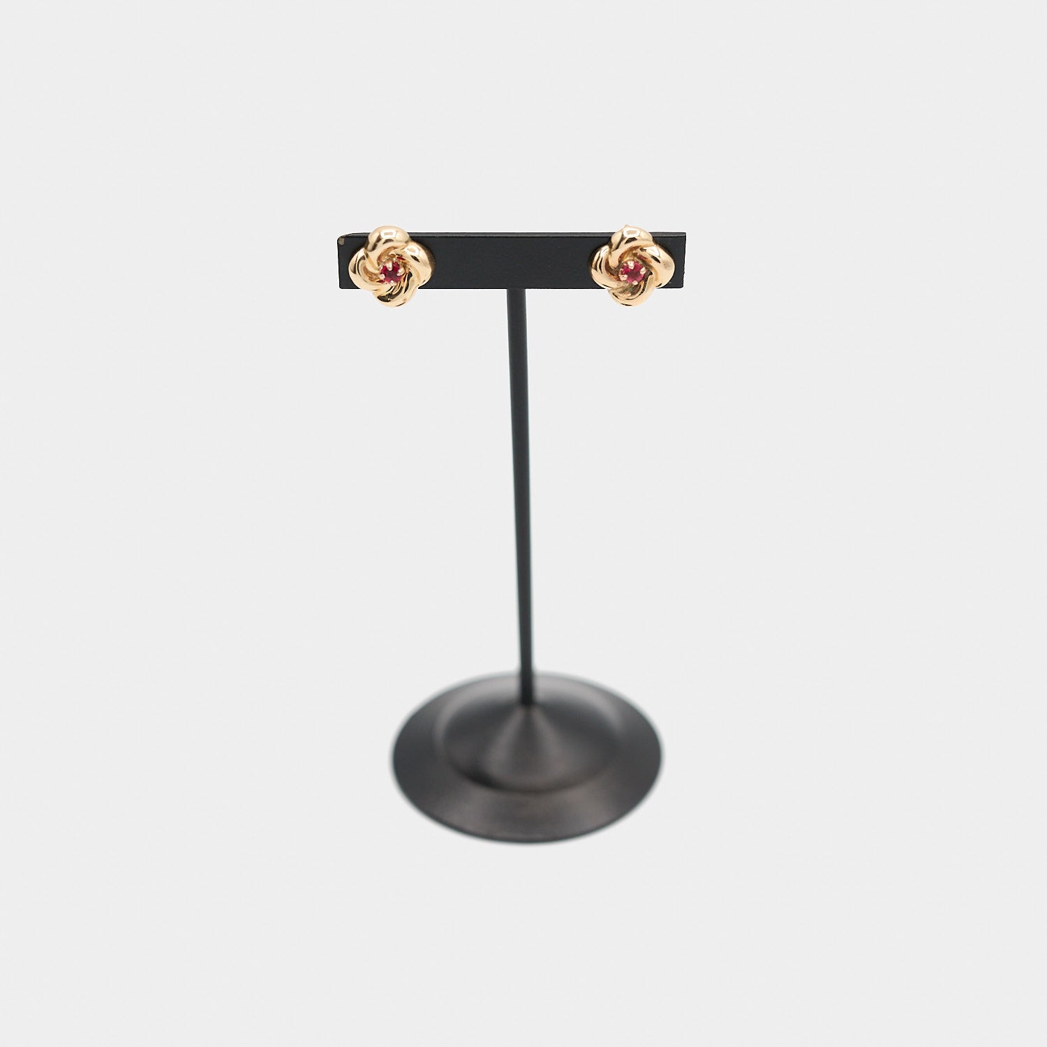 Verified pre-owned 10K yellow gold flower-shaped earrings set with vibrant red stones, displayed face-front on a jewelry stand.