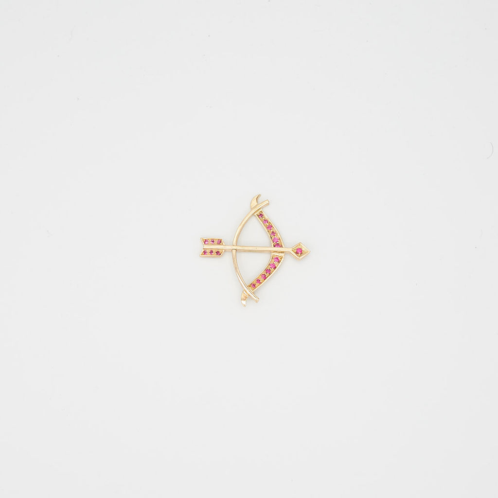 Close-up view of the 14K gold red stone bow and arrow pendant, laid flat, showcasing the stone placement and 11.11 gram total weight.