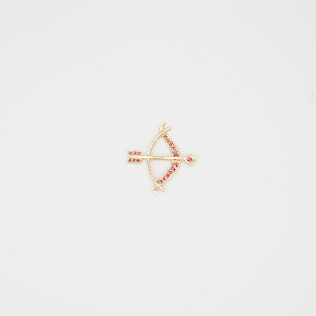 Close-up view of the 14K gold red stone bow and arrow pendant, laid flat, showcasing the stone placement and 11.11 gram total weight.