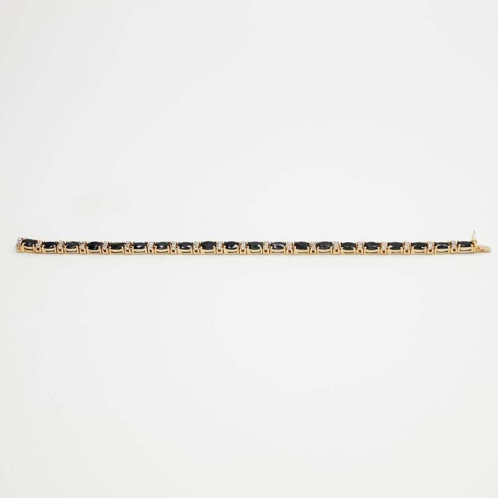 Close-up view of the 14K gold multi-gemstone tennis bracelet with blue and white stones, laid flat on a white background.