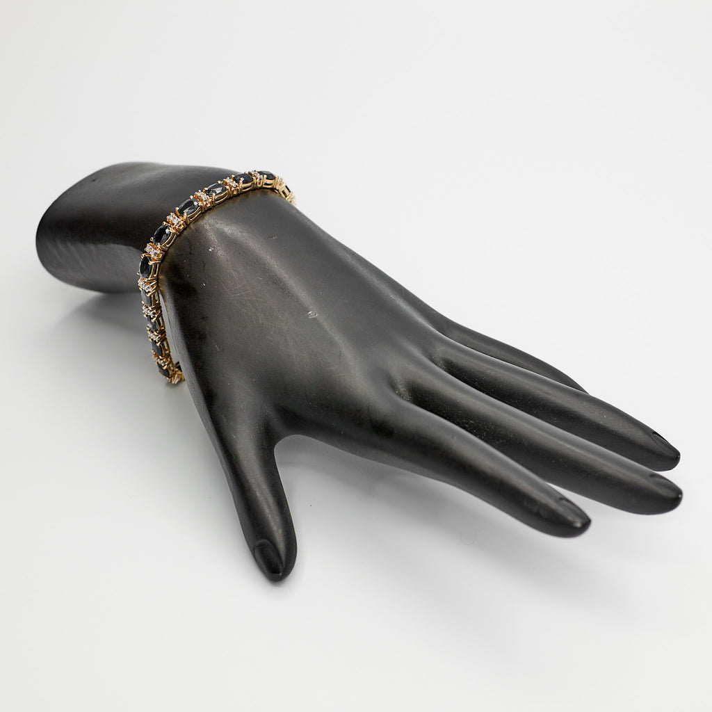 Pre-Owned 14K gold multi-stone tennis bracelet featuring blue and white stones, displayed on mannequin.