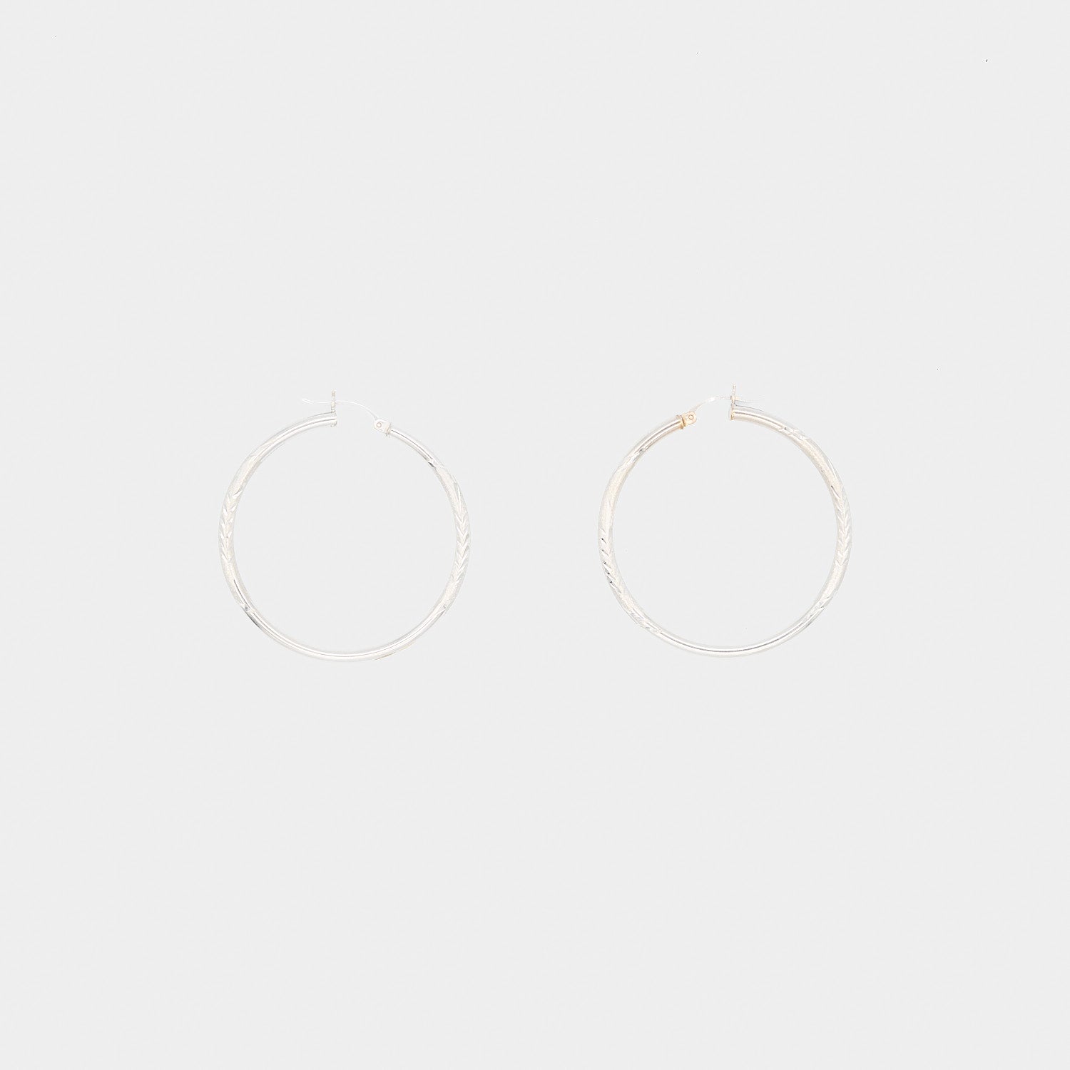 Close-up flat lay of the 14K white gold hoop earrings, showcasing the pair's condition and secure closure mechanism