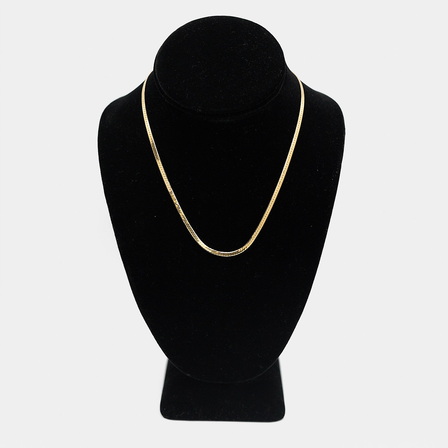 Verified pre-owned 14K yellow gold herringbone chain, 16.5 inches long, displayed on a black mannequin to show its fluid, flat-lay drape