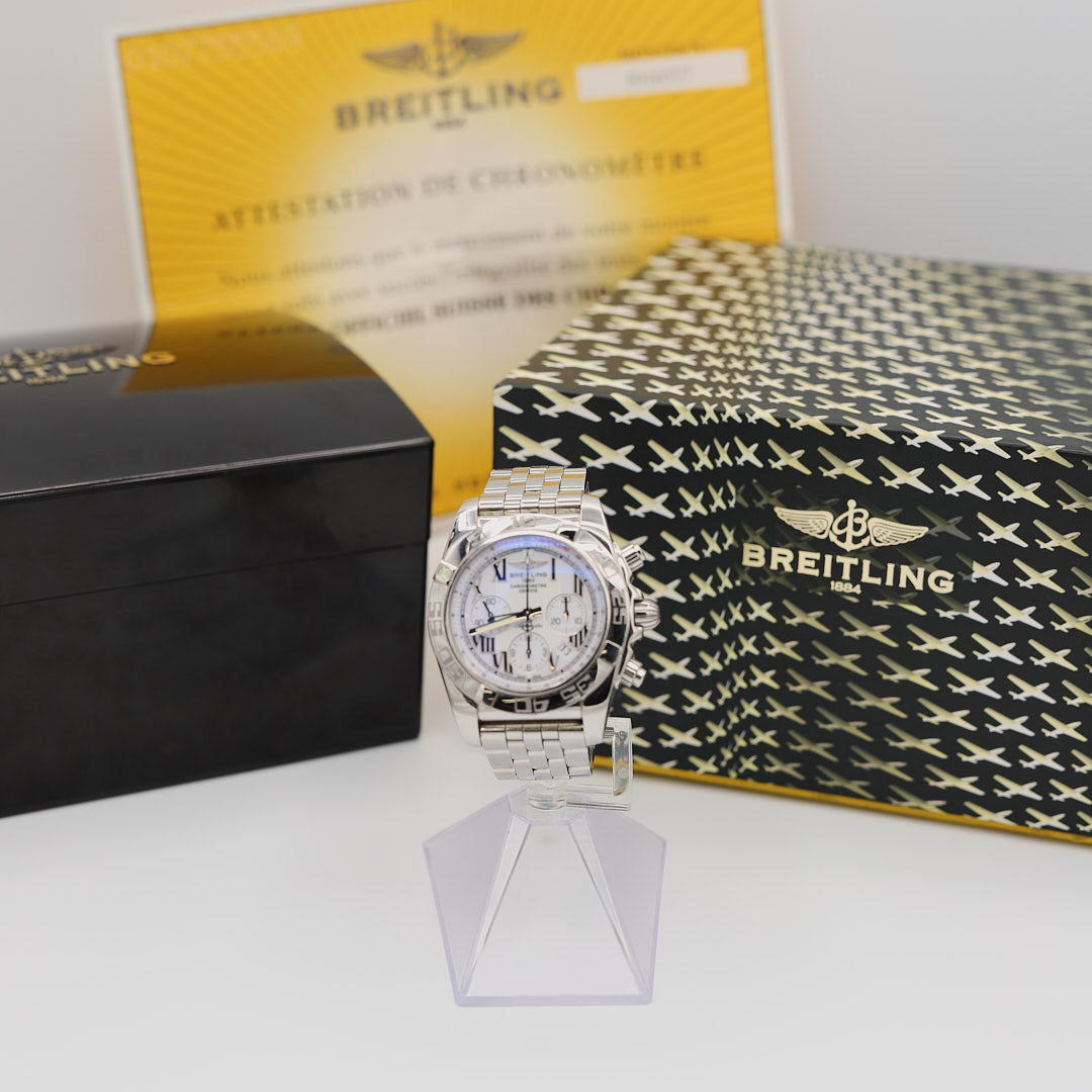 Front view of the Breitling Chronomat 44 watch, displayed alongside its original presentation box, warranty card, and paperwork.