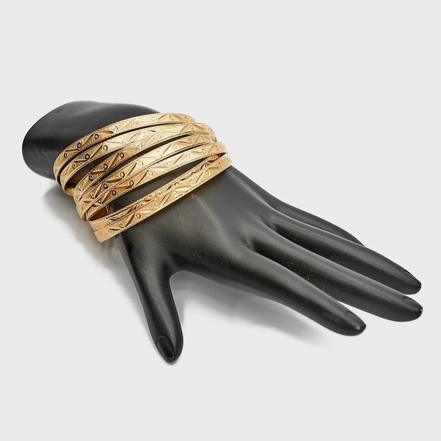 Pre-Owned set of seven 14K gold bangles, 51.57 grams total weight, styled on a wrist to show the stacked effect and 7.5 inch size.