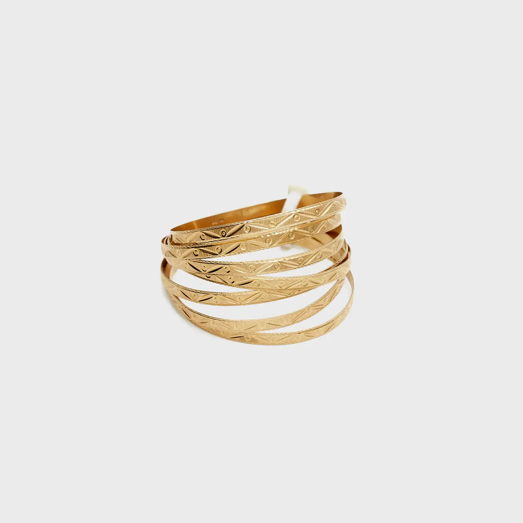 Close-up view of the set of seven 14K gold bangles laid flat, showcasing the intricate etched design and brilliant luster.