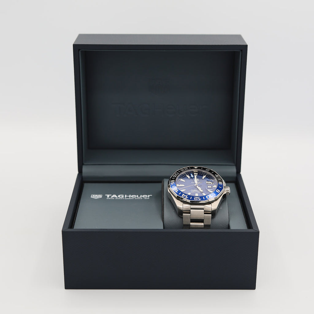 Front view of the TAG Heuer Aquaracer 43mm watch, displayed alongside its original presentation box and warranty card/paperwork.